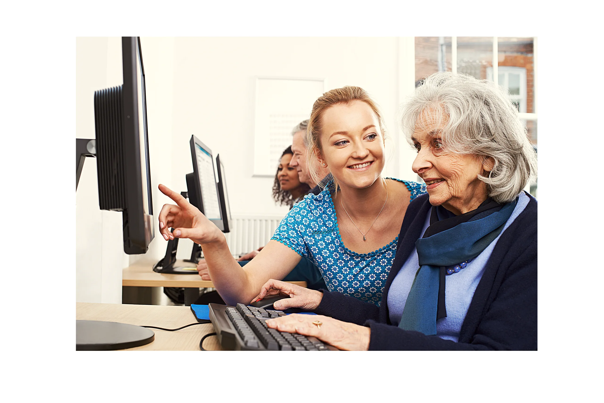 About 3 Tutor Helping Senior Woman In Computer Class