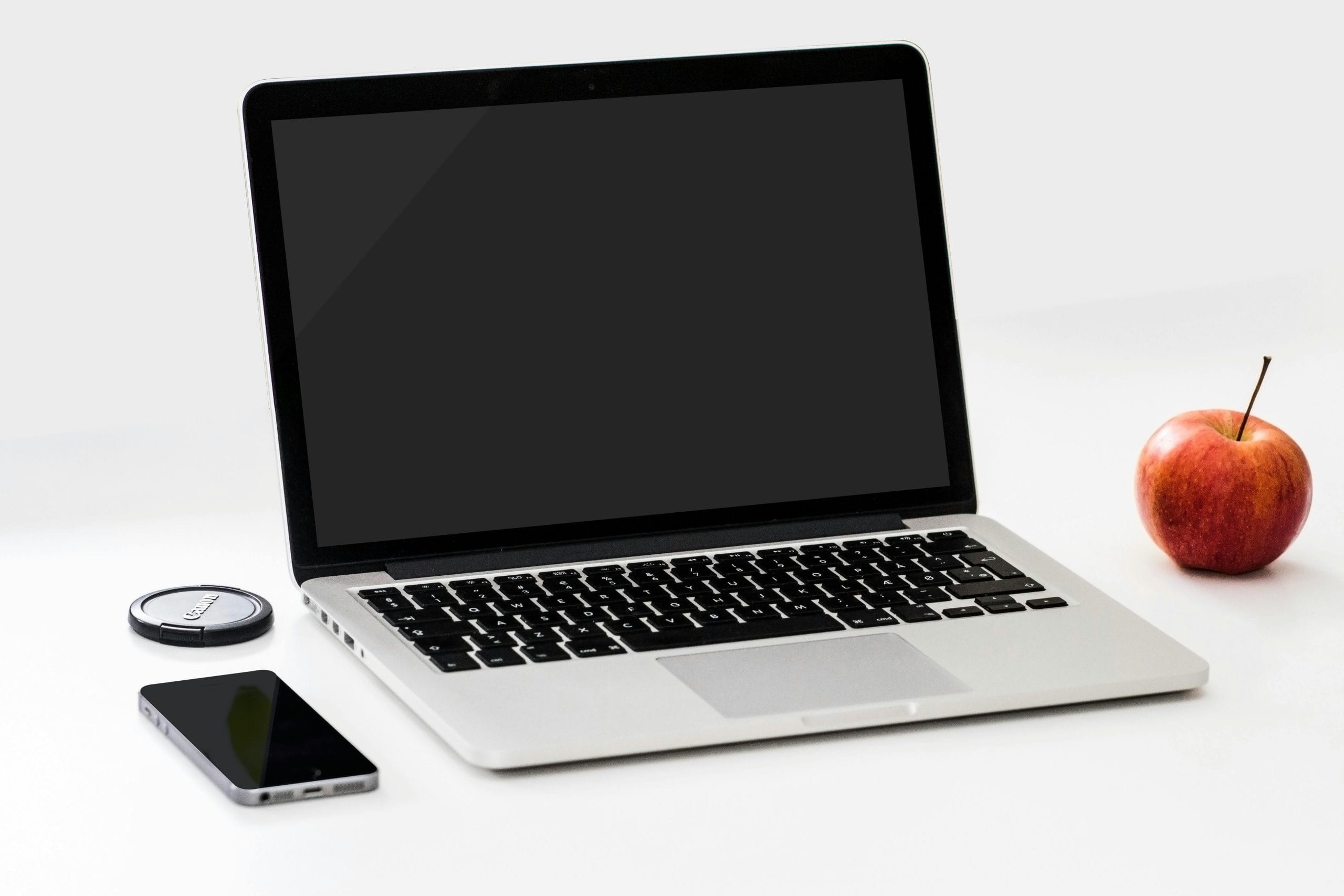 pexels-photo-18105 A minimalist workspace featuring a laptop, smartphone, and an apple on a clean white desk.